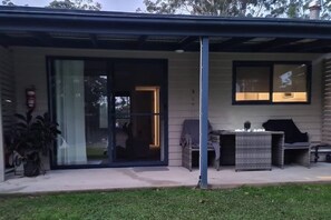 Un patio couvert avec une porte-fenêtre coulissante, du mobilier d’extérieur et un extincteur.