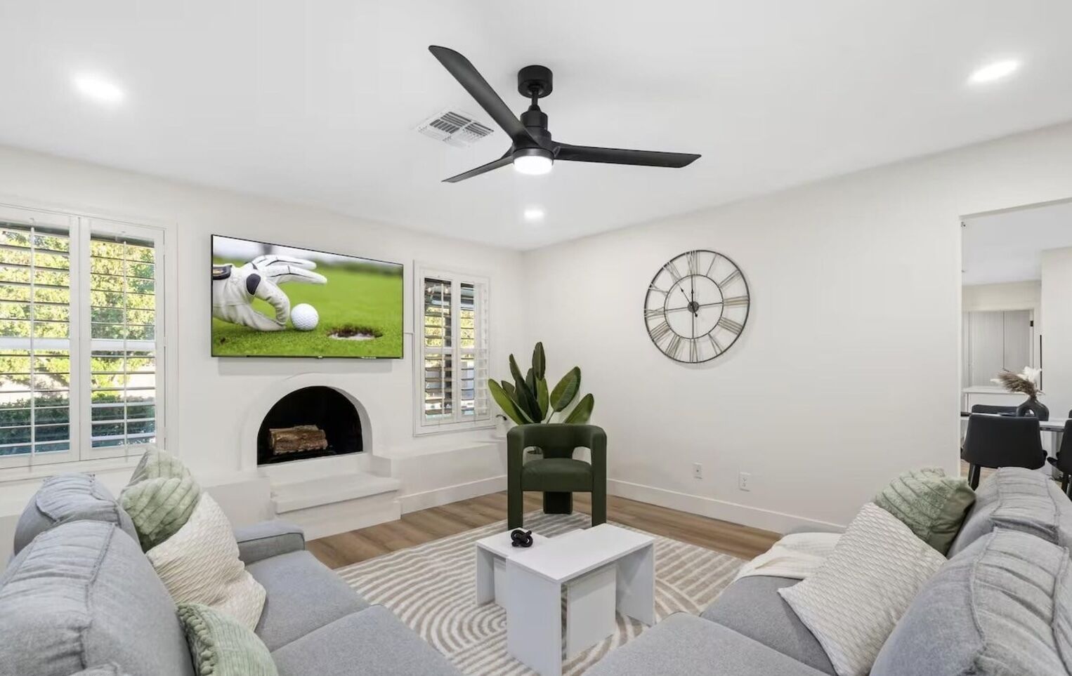 Een moderne woonkamer met een flatscreen televisie, een open haard, een klok en een plafondventilator.