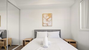 Ein Schlafzimmer mit einem Bett, zwei Nachttischen, einem Schminktisch und einem Wandbild.