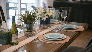 A dining table set with plates, glasses, and a bottle, surrounded by chairs and a vase with flowers. - Golf, Lake & Mountain Views, Pool, Spa, BBQ, Games (Indio)