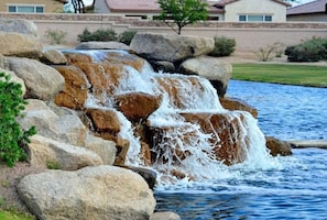 A waterfall feature with large rocks and a pool of water. - Golf Course + Lake Views, Pool, Spa, BBQ, Games - Sleep 20 (Indio)