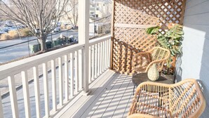 A covered porch with a white railing, wicker furniture, and a lattice screen. - Historic 2-bedroom house close to beltline in Cabbagetown, Atlanta (Atlanta)