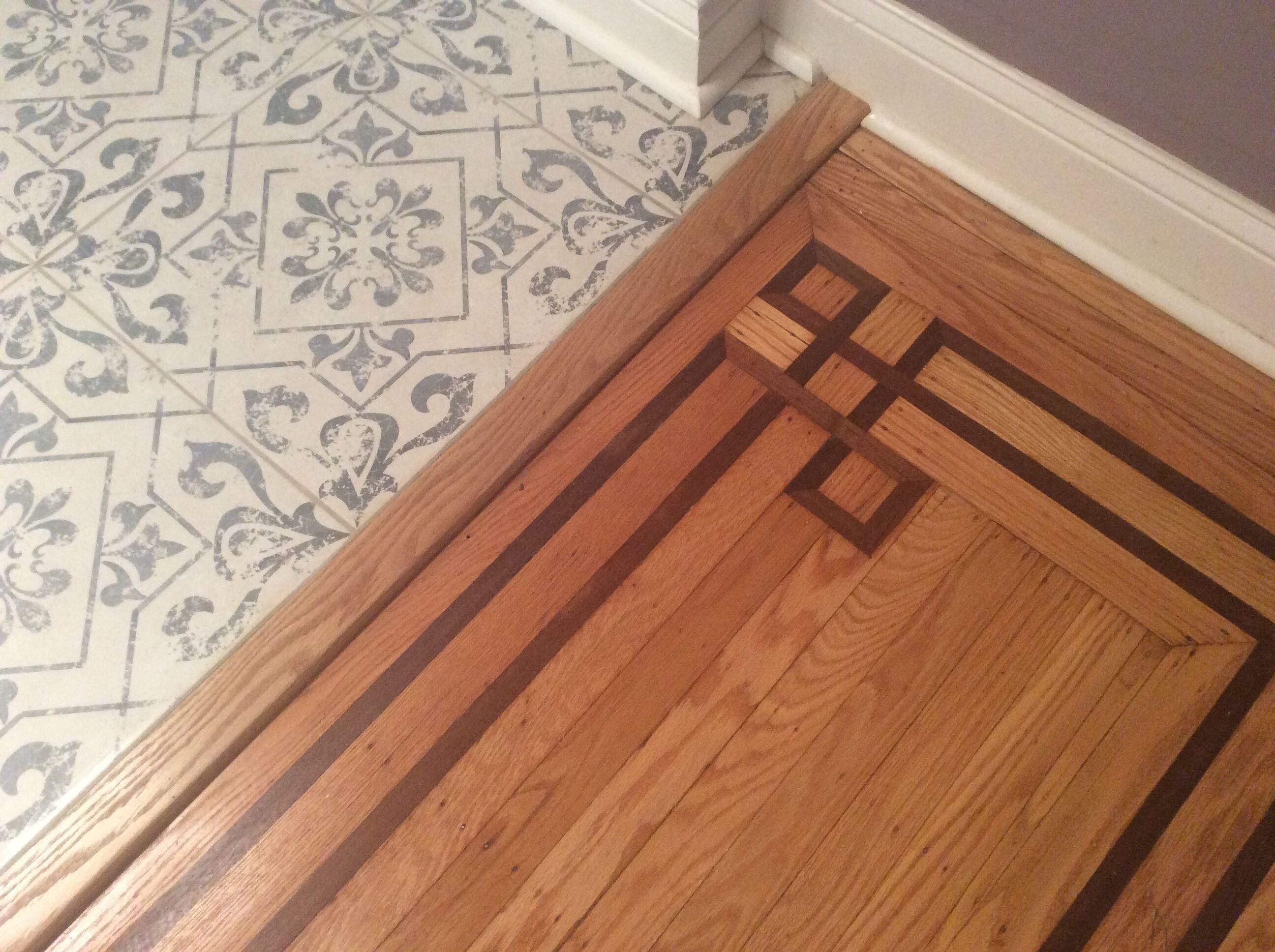 Un plancher en bois orné d’un motif géométrique et un carrelage au motif floral.