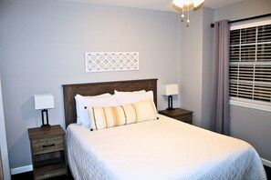 A neatly made bed with white and striped pillows, a wooden headboard, and two bedside tables with lamps. - Branson Condo next to Silver Dollar City (Indian Point)