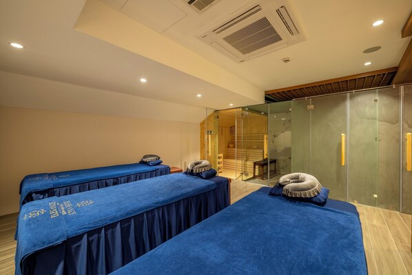 Habitación con tres camas cubiertas de ropa de cama azul, un separador de vidrio y un techo de madera.
