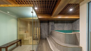 A spa area with a wooden bench, a glass-enclosed sauna, and a stone-tiled hot tub. - Elegance Ninh Binh Hotel  (Ninh Binh)