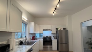Een moderne keuken met witte kasten, roestvrijstalen apparatuur en een marmeren aanrecht.