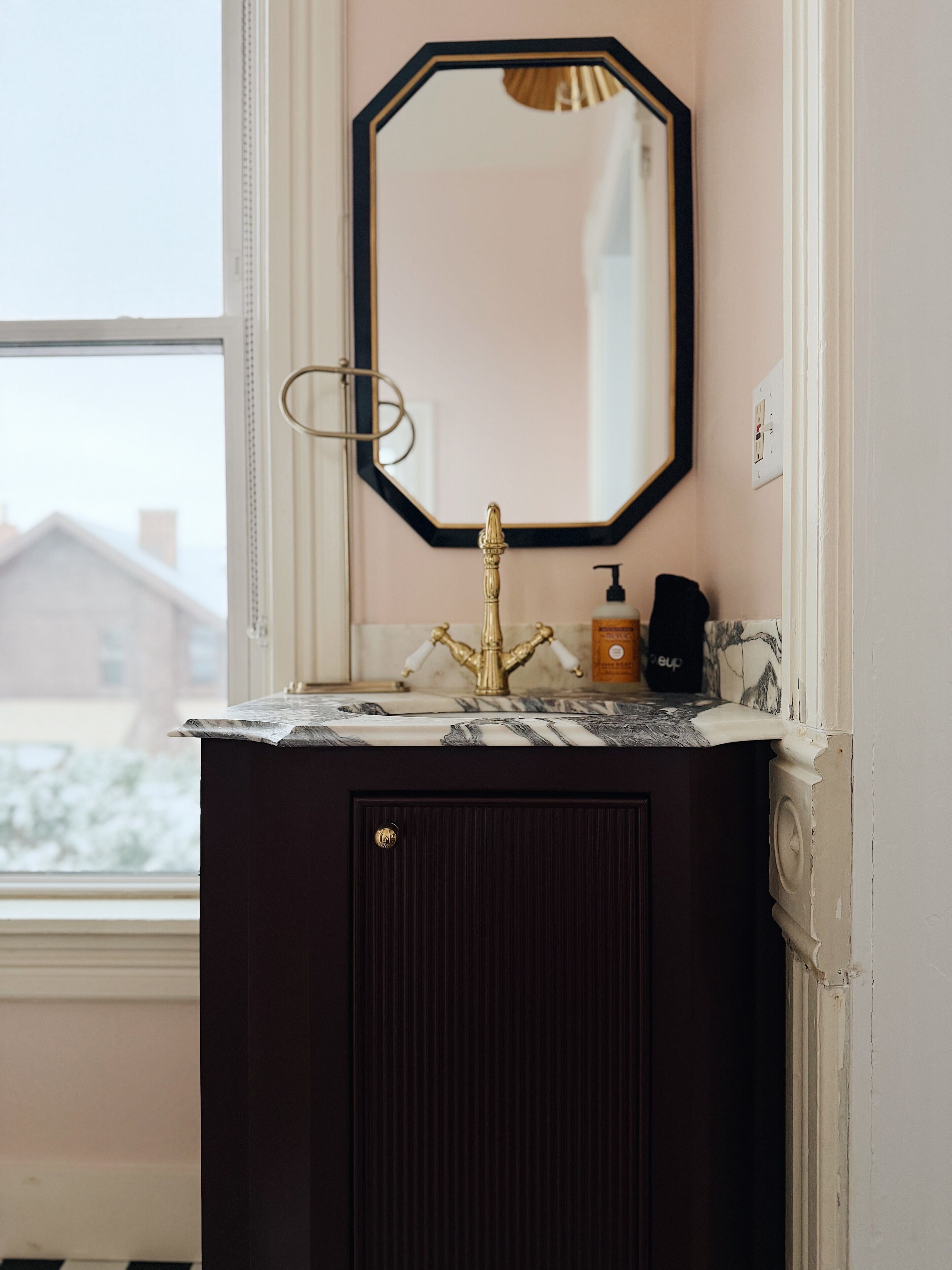 A bathroom with a dark wooden vanity, a gold faucet, and a marble countertop.