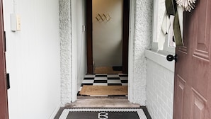 Un pasillo con piso a cuadros que conduce a una habitación con puerta.