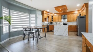Une cuisine moderne avec des meubles en bois, un îlot en marbre et un coin repas comprenant une table et des chaises.