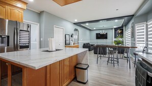 Une cuisine moderne dotée d’un plan de travail en marbre, de meubles en bois, d’appareils électroménagers en acier inoxydable et d’un coin repas avec un bar.
