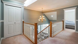 Un escalier avec une rampe en bois, un lustre et une porte donnant sur une autre pièce.