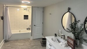 A modern bathroom with a white bathtub, a vanity with a mirror, and a sign that says "EVERYDAY is a fresh start." - Terrific 4-bedroom house in charming West Point (West Point)