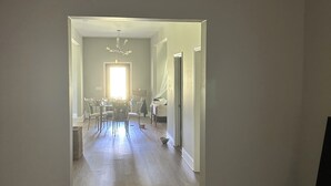 A spacious room with a high ceiling, a chandelier, and a dining area with chairs and a table. - Terrific 4-bedroom house in charming West Point (West Point)