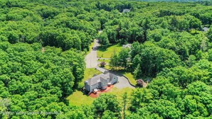 An aerial view of a residential area with a large house surrounded by dense green forest. - Spacious 7-bedroom country house in perfect Kingston retreat (Kingston)