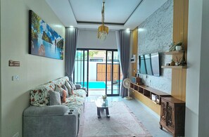 Un salon moderne avec un canapé, un téléviseur et une vue sur une piscine.