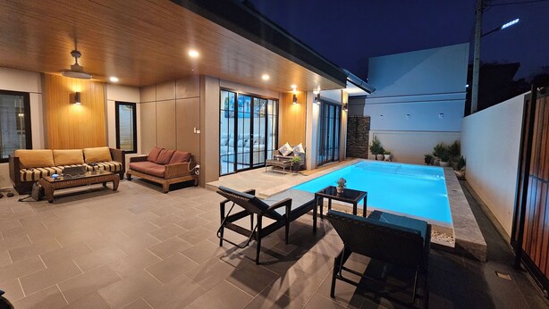 Un espace de vie extérieur moderne doté d’une piscine, de coins salon et d’un mur en bois.