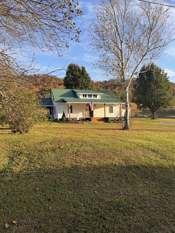 A single-story house with a green roof, a front porch, and an American flag. - Relaxing Farmhouse in beautiful Butler (Butler)