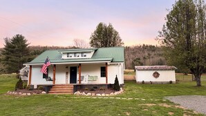 A single-story house with a green roof, a porch with a bench, and a small shed. - Relaxing Farmhouse in beautiful Butler (Butler)