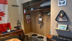 Interior acogedor de una cabaña con un escritorio de madera, dos taburetes, una mesita, una bandera y un cartel que dice 'is better at the cabin'.
