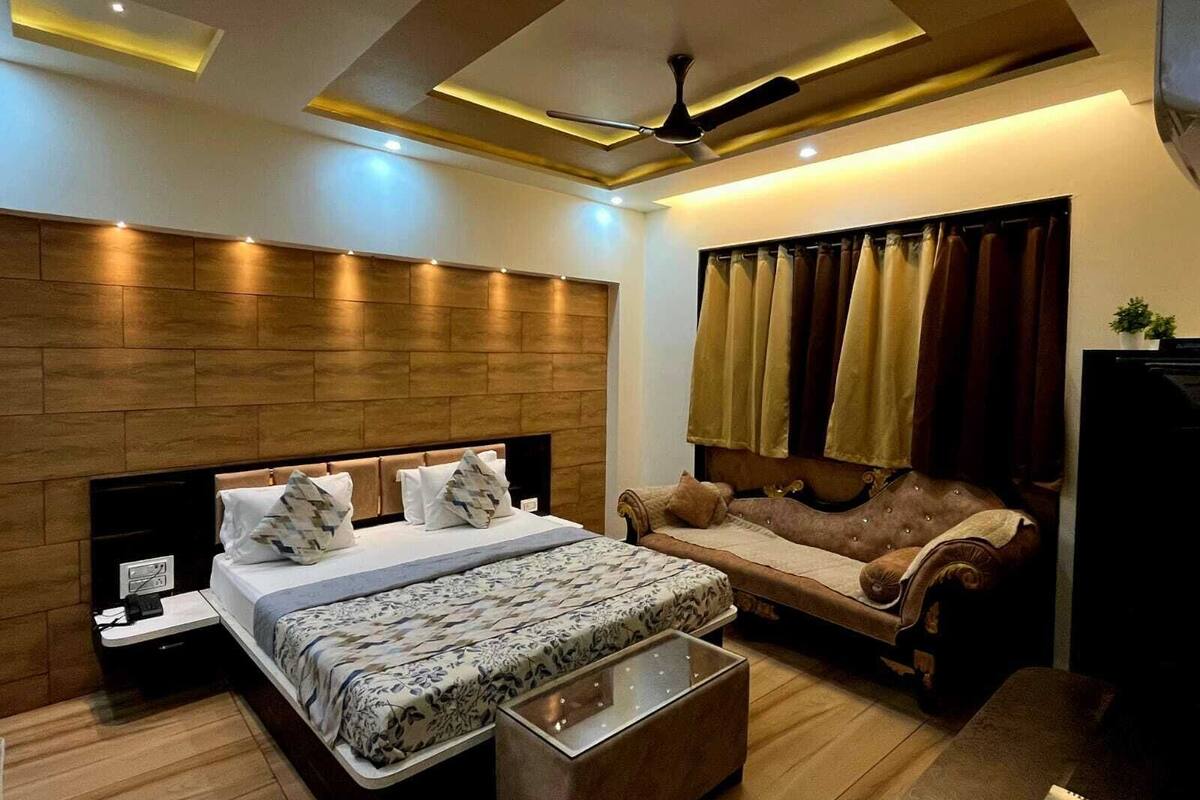 A modern bedroom with a large bed, a sofa, a coffee table, and a ceiling fan.