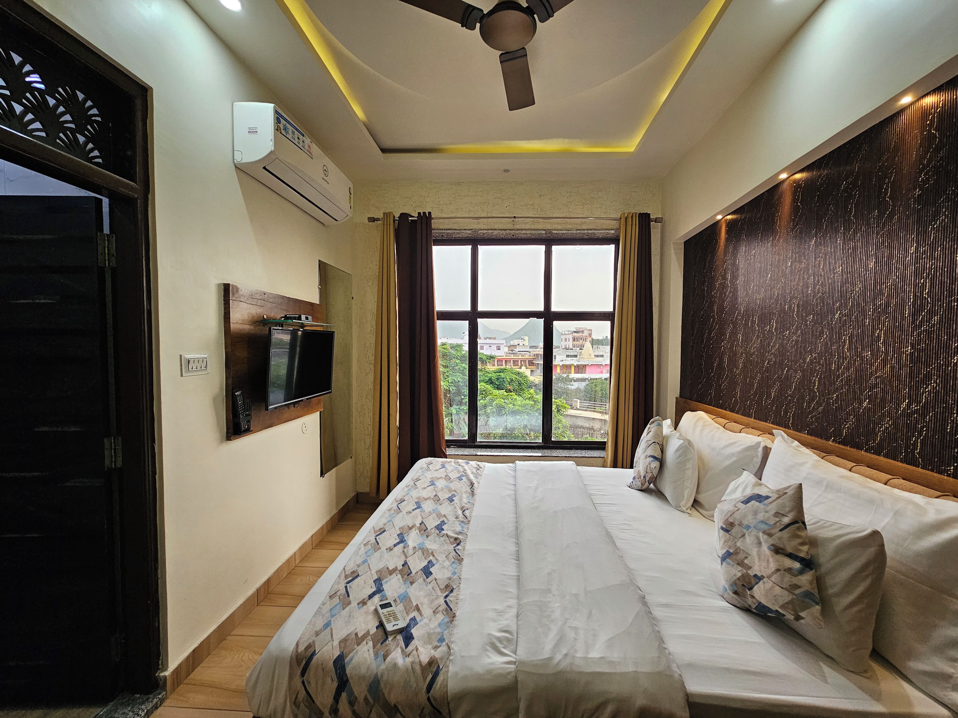 Una habitación de hotel con una cama, televisor, aire acondicionado y vista a la ciudad.