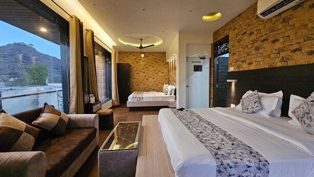 A hotel room with a large bed, a sofa, a small table, and a view of the outdoors. - Hotel Leela Vilas- A Boutique Hotel (Pushkar)