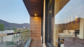 A modern balcony with a herringbone floor pattern, glass railings, and a view of the surrounding area. - Hotel Leela Vilas- A Boutique Hotel (Pushkar)