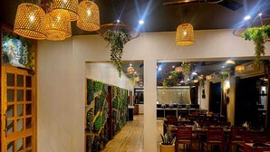 A restaurant interior with wooden flooring, hanging woven light fixtures, and a central dining area with tables and chairs. - Hotel Leela Vilas- A Boutique Hotel (Pushkar)