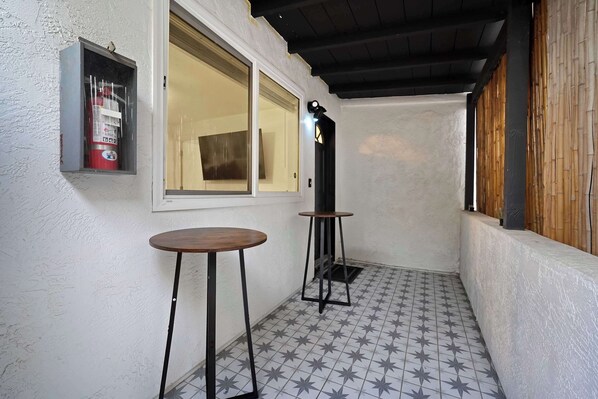 A small, enclosed balcony area with a tiled floor, two tables, a fire extinguisher, and a window. - Explore South Park from 2-Story Home Sleeps 8 (San Diego)
