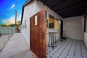 A small, single-story building with a wooden gate, a small table, and a tiled floor. - Explore South Park from 2-Story Home Sleeps 8 (San Diego)