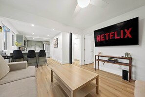 A modern living room with a wooden coffee table, a beige sofa, and a TV displaying the Netflix logo. - Explore South Park from 2-Story Home Sleeps 8 (San Diego)