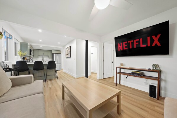 A modern living room with a wooden coffee table, a beige sofa, and a TV displaying the Netflix logo. - Explore South Park from 2-Story Home Sleeps 8 (San Diego)
