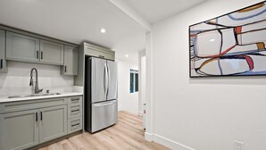 Una cocina moderna con gabinetes grises, electrodomésticos de acero inoxidable y piso de madera.