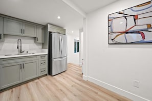 A modern kitchen with grey cabinets, stainless steel appliances, and a wooden floor. - Explore South Park from 2-Story Home Sleeps 8 (San Diego)