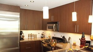 Een moderne keuken met houten kastjes, roestvrijstalen apparatuur en hanglampen.