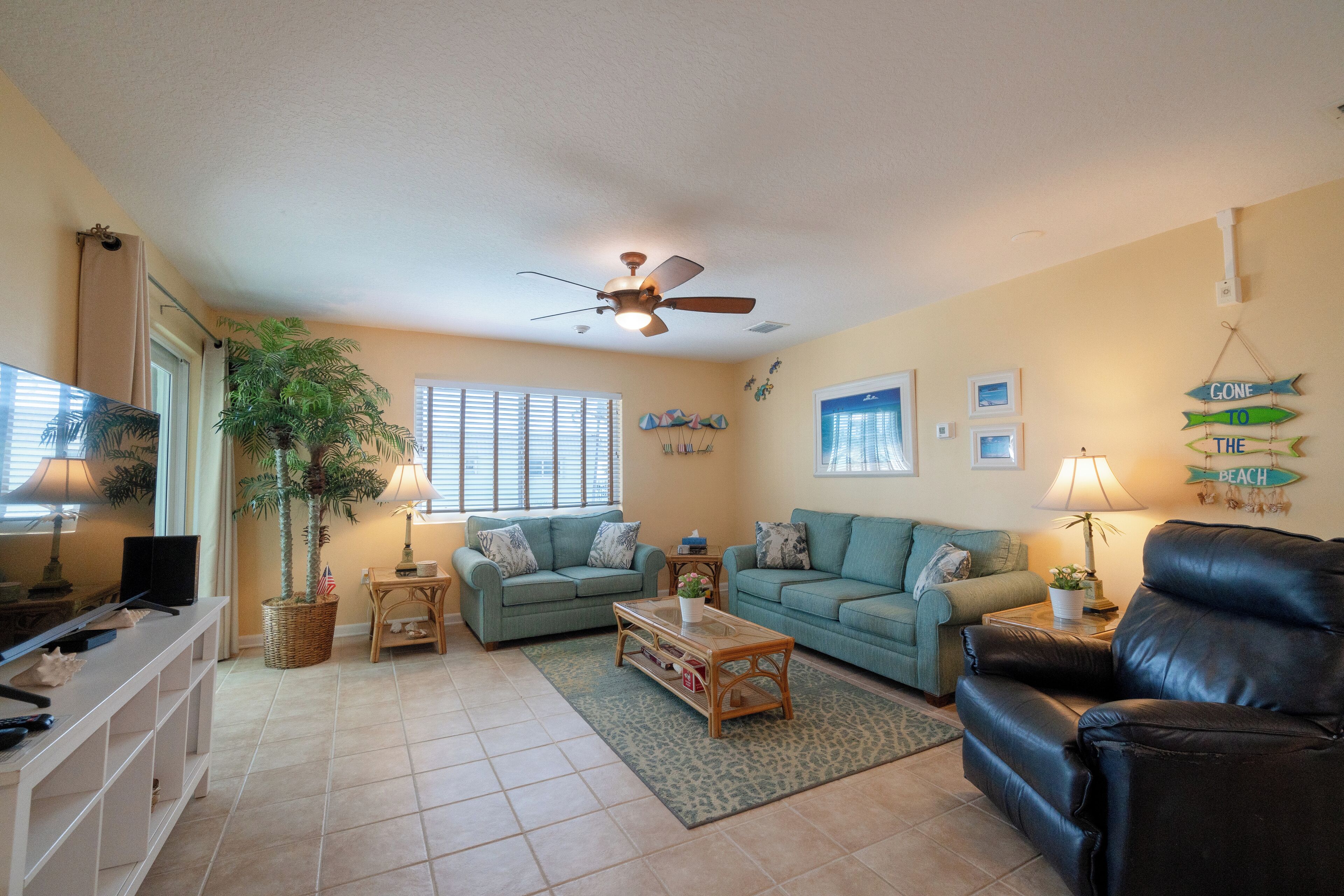 A living room with two sofas, a coffee table, a TV, and a ceiling fan.