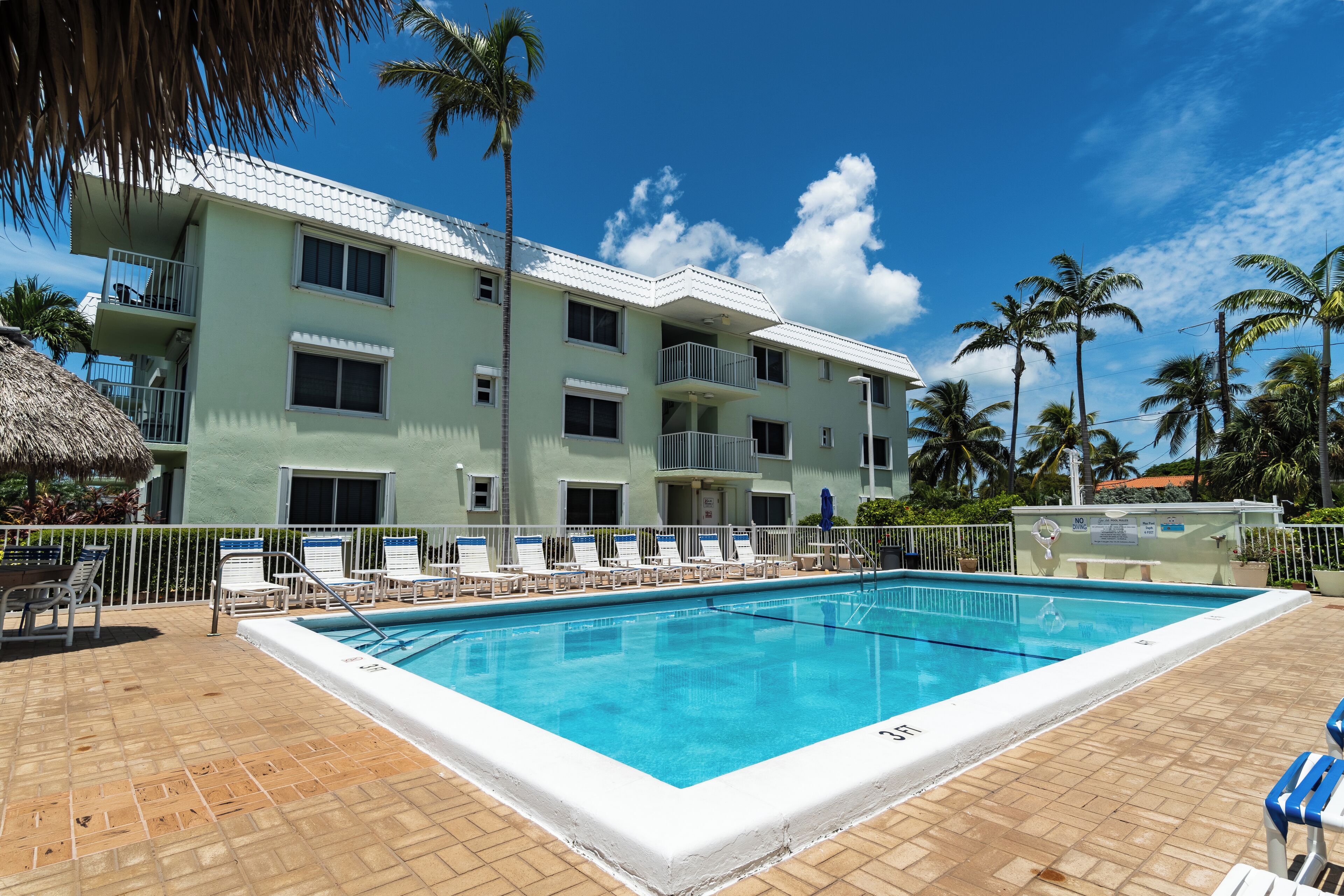 Une piscine avec des chaises longues et un bâtiment doté de balcons.
