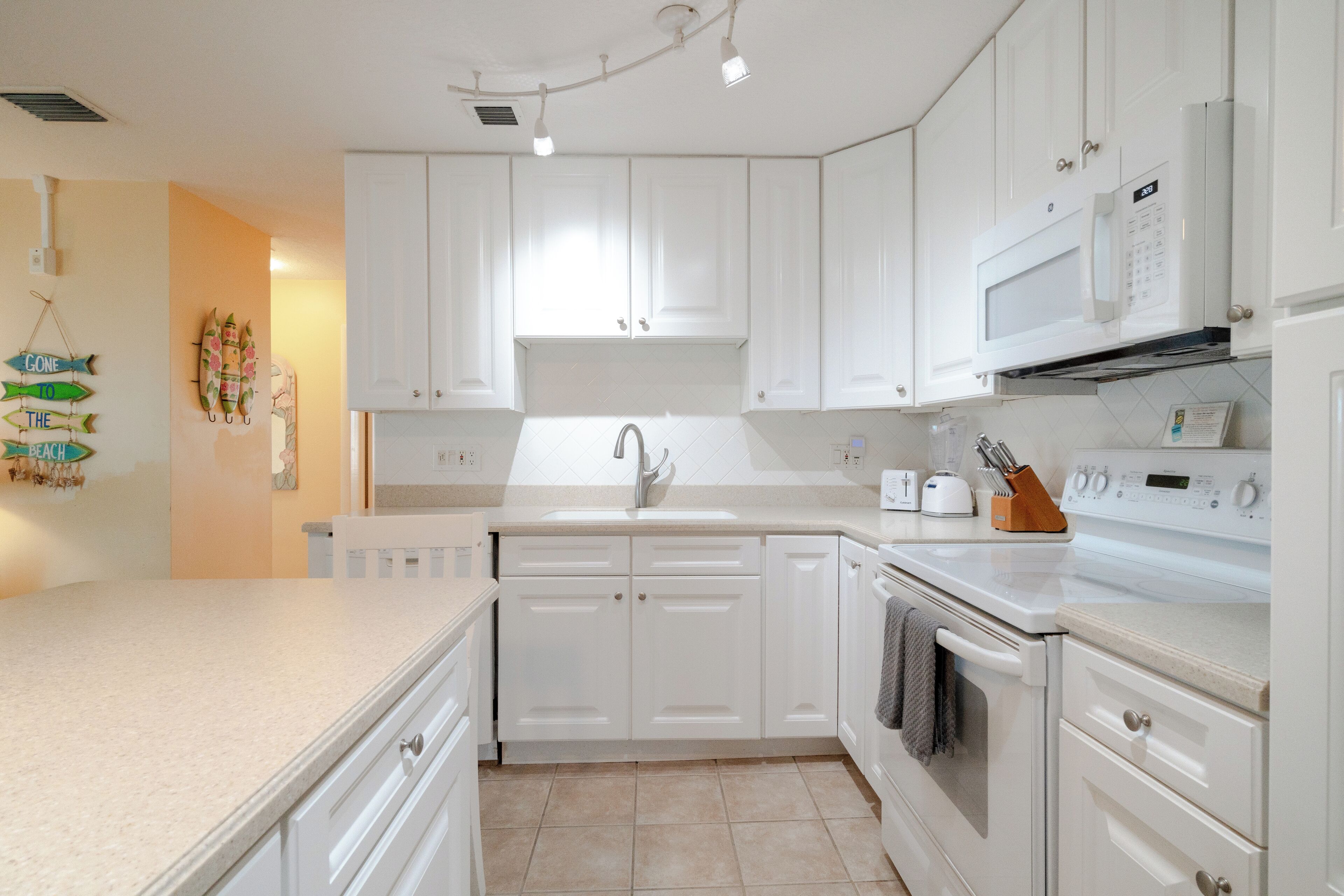 A modern kitchen with white cabinets, a built-in microwave, and a stove.