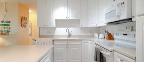 A modern kitchen with white cabinets, a built-in microwave, and a stove.
