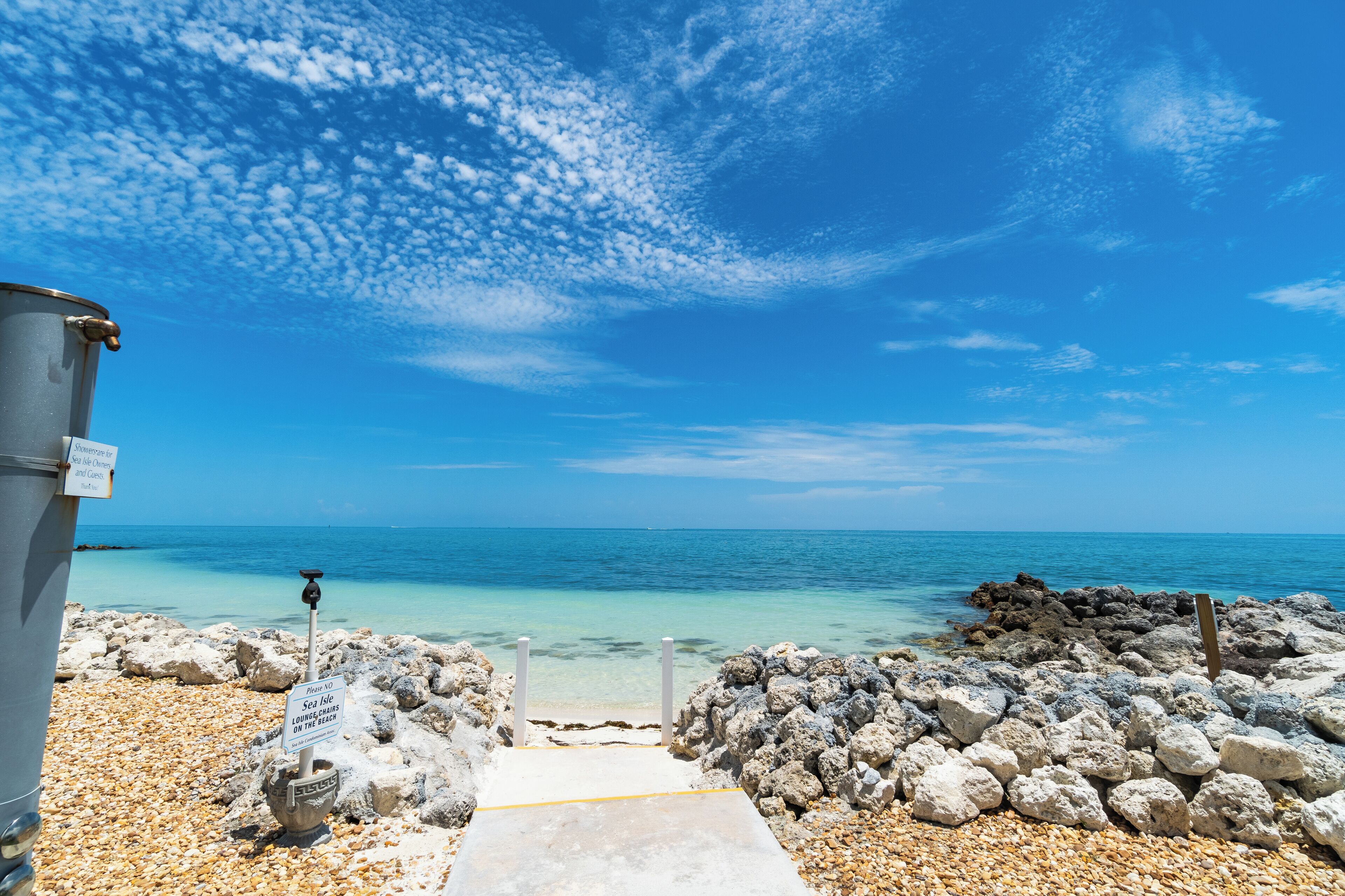 A rocky beach with a clear blue sky and turquoise sea.