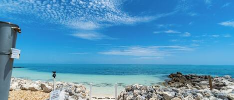 A rocky beach with a clear blue sky and turquoise sea.
