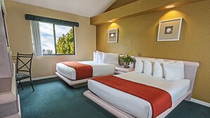 Ein Hotelzimmer mit zwei Betten, einem Sessel, einem Fenster mit Blick auf Bäume und zwei an der Wand befestigten Bildern.