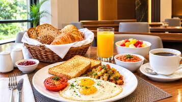 A breakfast setting with toast, eggs, tomatoes, and a fruit bowl.