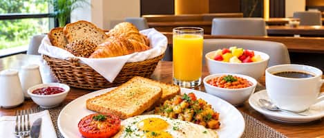 Un desayuno con tostadas, huevos, tomates y un bol de fruta.