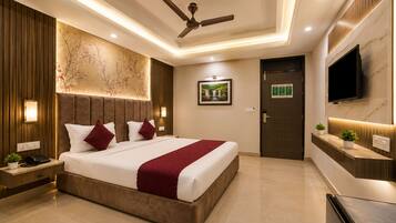 A modern hotel room with a large bed, a ceiling fan, a flat-screen TV, and a wall-mounted TV.