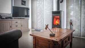 Un soggiorno moderno con un tavolino in legno, un caminetto, una televisione e un angolo cottura sullo sfondo.