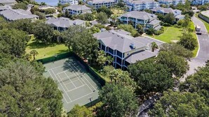 Un quartier résidentiel composé de plusieurs maisons à deux étages, d’un court de tennis et, au loin, d’un lac.