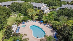 A resort with a large pool surrounded by lounge chairs and palm trees. - Designer-Renovated Condo in a Gorgeous Tropical Oasis! (Davenport)