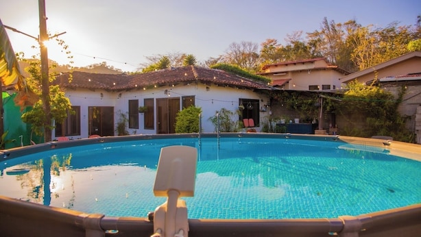 A swimming pool with a lounge chair in the foreground, surrounded by houses with tiled roofs and greenery. - Casa San Isidro is a sparkling clean, and family friendly house (Copán Ruinas)
